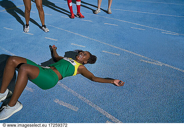 Tired track and field athlete laying on sunny track