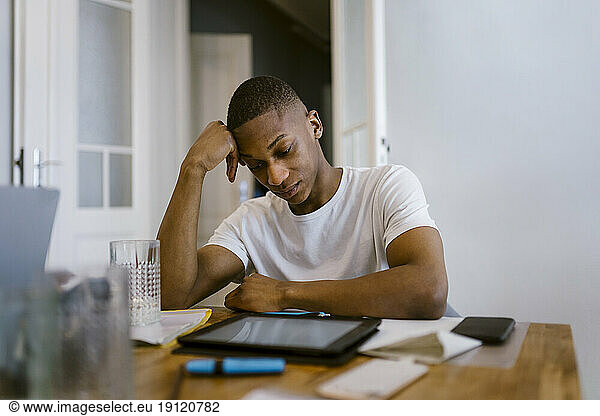 Tired young man leaning on elbow while studying at home