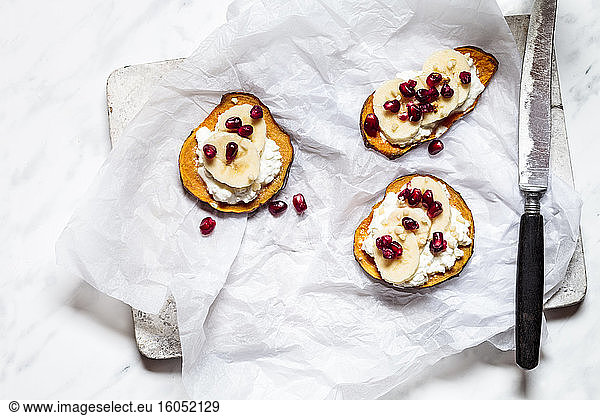 Toasted slices of sweet potato with cottage cheese  banana and pomegranate seeds