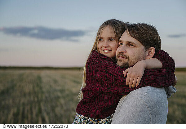 Tochter umarmt Vater beim Anblick des Sonnenuntergangs
