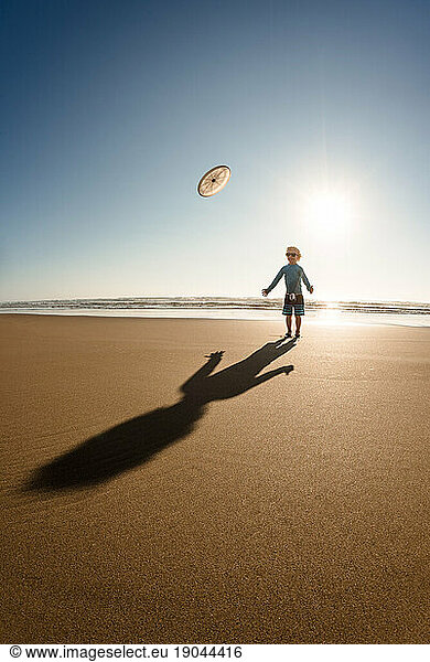 Toddler boy playing Frisbee on a sunny day at the beach