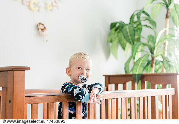 Toddler Boy Smiles Peacefully at Camera in Crib in the Morning