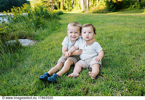 toddler boy with his baby brother sitting on a summer day