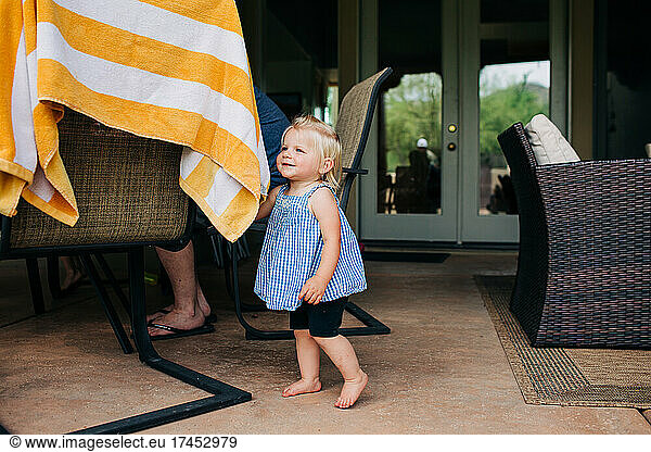Toddler Caucasian girl smiles while playing in Arizona backyard