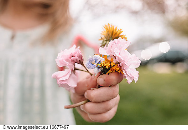toddler girl holding a small bouquet of wildflowers and weeds
