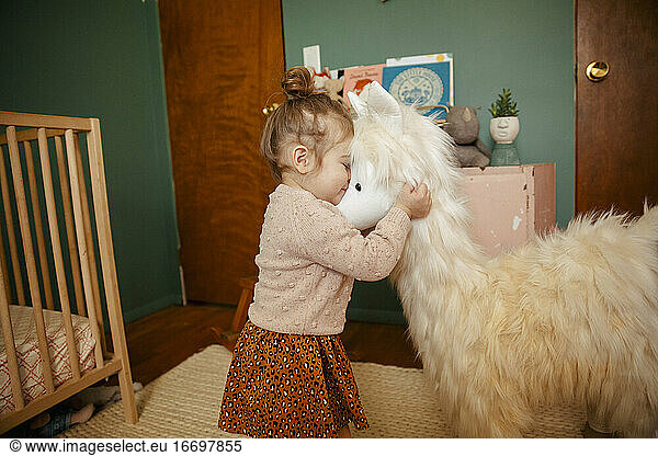 Toddler girl hugging her stuffed animal happily