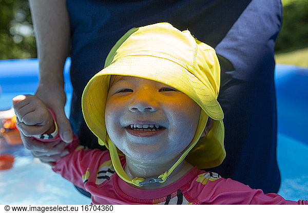 Toddler Girl in Kiddie Swimming Pool Smiles with Mom Holding Her