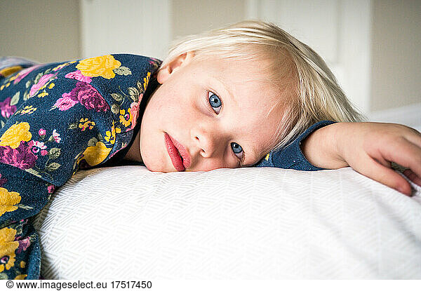 toddler girl laying on her side staring into camera