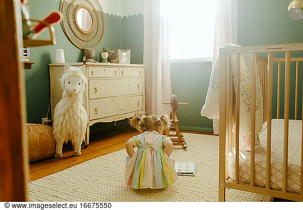Toddler girl reading a book in her room