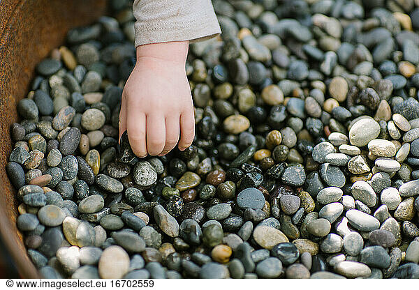 Toddler hand picking up small stones