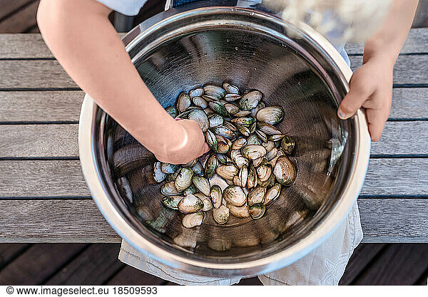 Toddler holding a large bowl of fresh shellfish