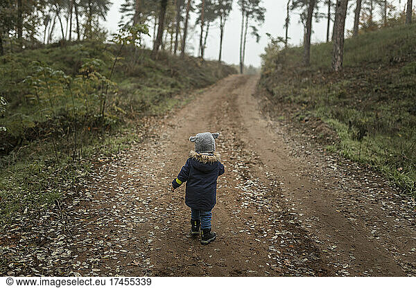 Toddler in middle of forest on a trail during foggy weather