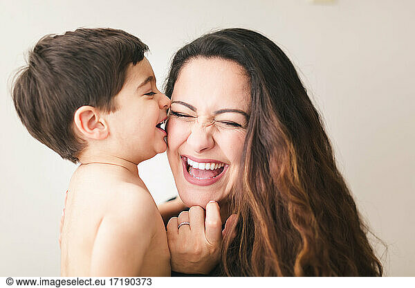Toddler kissing his mom on the cheek  mom laughing.