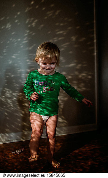 toddler standing in sparkling sunlight in hallway