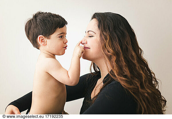 Toddler touching his mom's nose.