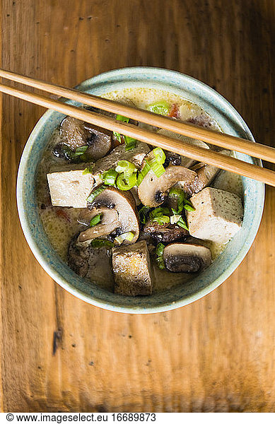 Tofu and Mushroom soup in blue bowl with chopsticks closeup