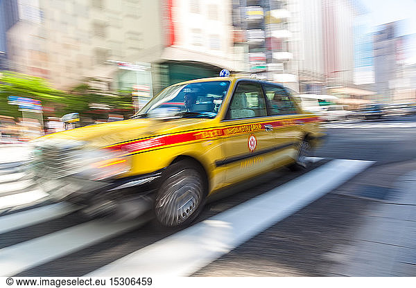 TOKYO  JAPAN ï¾– JUNE 06 2015: Motion blurred yellow taxi cab on pedestrian crossing  Tokyo  Japan.