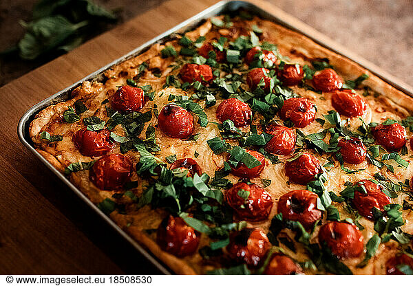tomato tart on a sheet pan on a wood cutting board in a kitchen