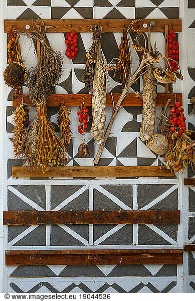 Tomatoes  garlic and herbs drying on a traditionally decorated wall.