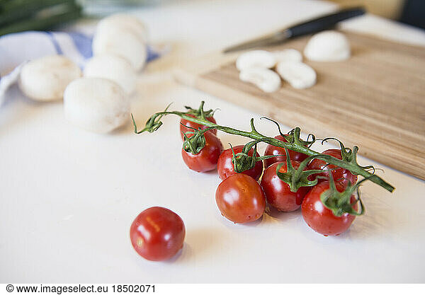 Tomatoes  mushrooms and cutting board on kitchen table