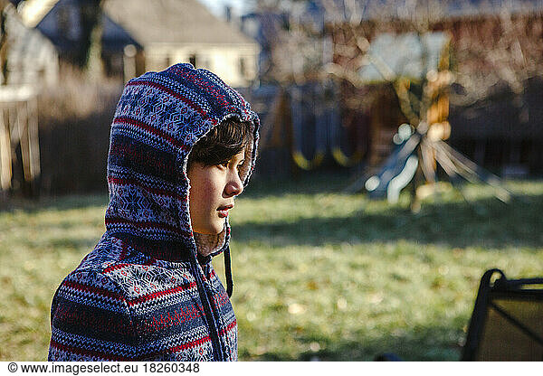 Top half of a child wearing hooded sweatshirt in sunlight