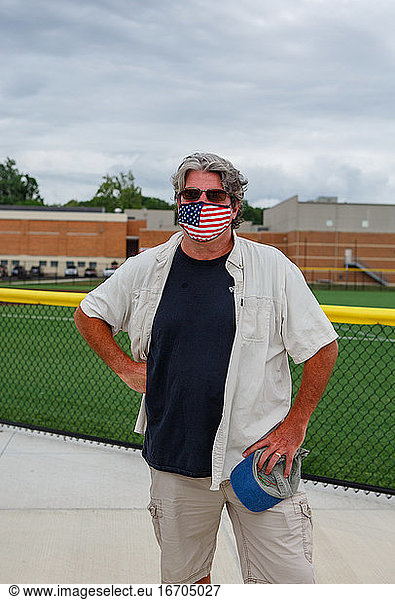 Top half of man wearing an American Flag mask outside of High School