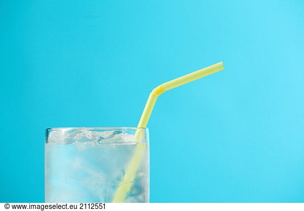 Top portion of very full glass of water with yellow drinking straw