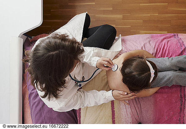 Top view of a pediatric doctor examine little girl with stethosc