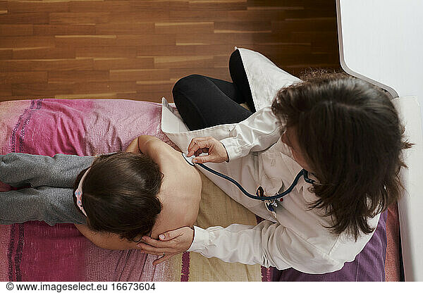 Top view of a pediatric doctor examine little girl with stethosc