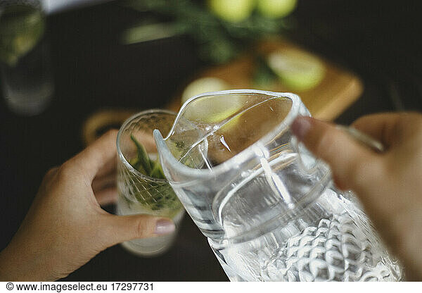 Top view of pouring water from a jug into a glass for mojito