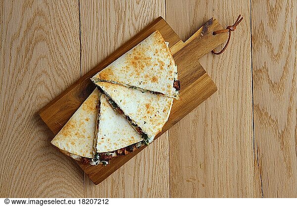 Top view of tortillas stuffed with meat  vegetables and cheese on serving plate