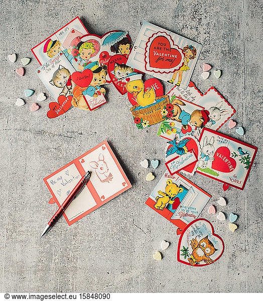 Top view of vintage Valentine's cards and candy on grey background.