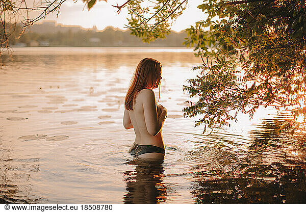 Topless woman in water at sunset