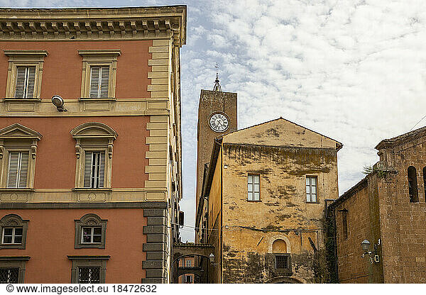 Torre del Moro and Palazzo Conte Bracci buildings under cloudy sky in Orvieto  Italy