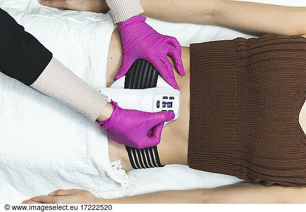 Torso of young woman having abdomen massage at aesthetic center