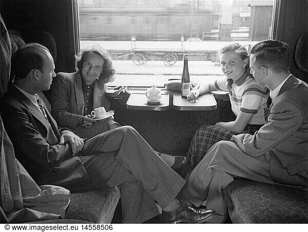 tourism  two couples in train compartment  1950s  50s  20th century  historic  historical  railway  railroad  railways  railroads  compartment car  carriage  interior view  inside  inwards  inward  interior  inner  inboard  train traveler  train travelers  passengers  train journey  train journeys  train ride  train rides  stop  break  breaks  conversation  conversations  people  half length