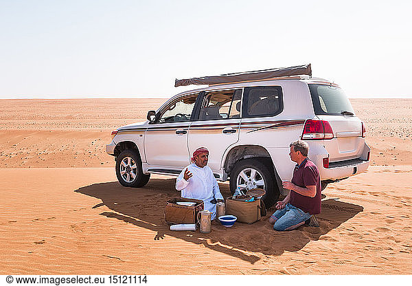Tourist bei einer Kaffeepause mit seinem örtlichen Fahrer in der Wüste  Wahiba Sands  Oman