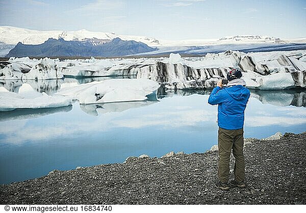 Tourist beim Fotografieren der Jokulsarlon Gletscherlagune  einem Gletschersee mit Eisbergen im Südosten Islands