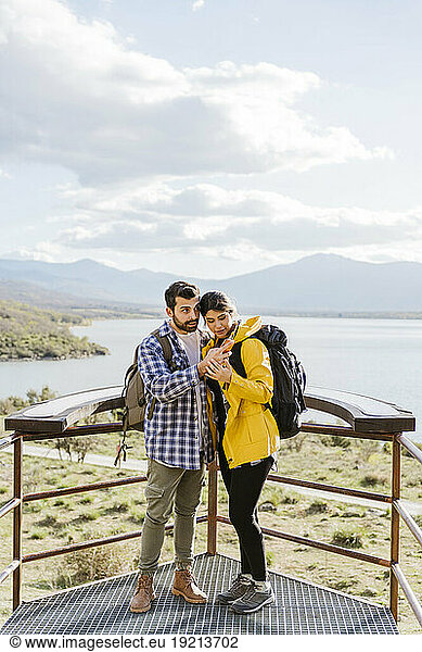 Tourist couple sharing smart phone standing at observation point