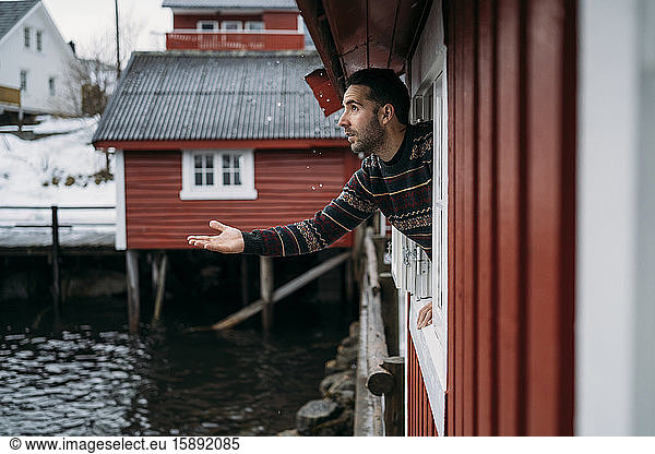 Tourist  der sich aus dem Fenster einer Hütte lehnt  Lofoten  Norwegen