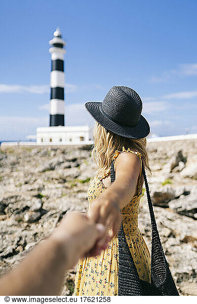 Tourist looking at Artrutx Lighthouse holding hand of man  Minorca  Spain