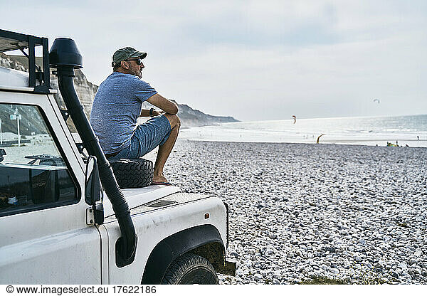Tourist sitting on car at beach