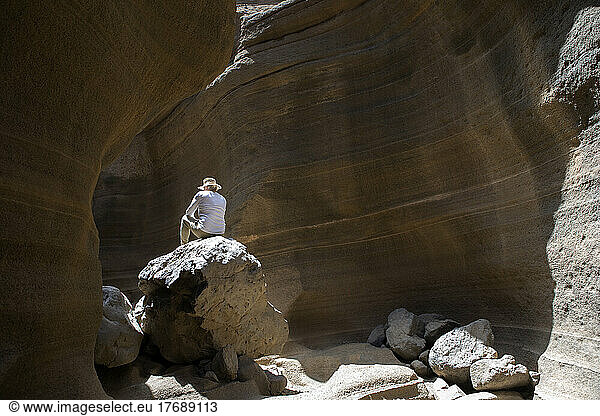 Tourist sitting on rock in desert area at Grand Canary  Barranco De Las Vacas  Spain