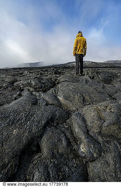 Tourist standing on petrified lava  volcanic stone in bizarre shapes  lava field  volcanic eruption  active table volcano Fagradalsfjall  Krýsuvík volcanic system  Reykjanes Peninsula  Iceland  Europe