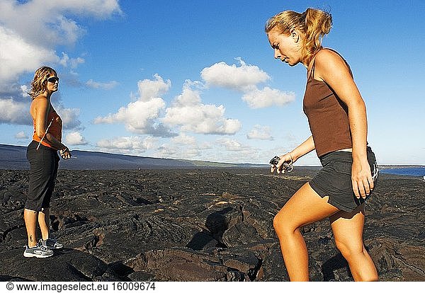 Touristen bei einem Spaziergang über die schwarzen Lavaberge in der Nähe der Küste und der Chain of Crater Road. Hawai'i Volcanoes National Park. Big Island. Hawaii. Lavafelder und der Pazifische Ozean mit einem Fischaugenobjektiv  Volcano National Park. Jüngster Lavastrom  Lava vom Typ Pahoehoe. Der 1916 gegründete Hawai?i Volcanoes National Park ist ein Nationalpark der Vereinigten Staaten und liegt im US-Bundesstaat Hawaii auf der Insel Hawaii. Er umfasst zwei aktive Vulkane: Kilauea  einer der aktivsten Vulkane der Welt  und Mauna Loa  der mächtigste subaerische Vulkan der Welt. Der Park bietet Wissenschaftlern Einblicke in die Entstehung der Hawaii-Inseln und in laufende Studien über die Prozesse des Vulkanismus. Für Besucher bietet der Park dramatische Vulkanlandschaften sowie Einblicke in eine seltene Flora und Fauna. In Anerkennung seiner herausragenden Naturwerte wurde der Hawai?i Volcanoes National Park 1980 zum internationalen Biosphärenreservat und 1987 zum Weltnaturerbe ernannt. Im Jahr 2000 wurde empfohlen  den Namen durch den Hawaiian National Park Language Correction Act of 2000 zu ändern und die hawaiianische Schreibweise beizubehalten  aber dieser Gesetzentwurf wurde nicht angenommen. Im Jahr 2012 wurde der Hawai'i Volcanoes National Park auf dem 14. Quartal der America the Beautiful Quarters Serie geehrt.