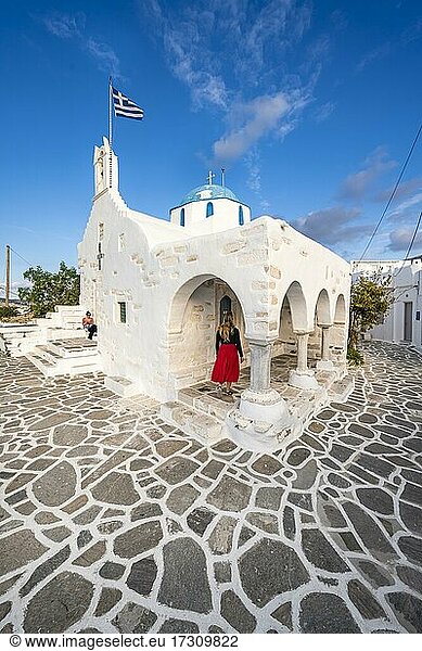 Touristin mit rotem Kleid  Blaue-Weiße Griechisch-Orthodoxe Kirche Agios Nikolaos mit Griechischer Flagge  Parikia  Paros  Kykladen  Ägäis  Griechenland  Europa