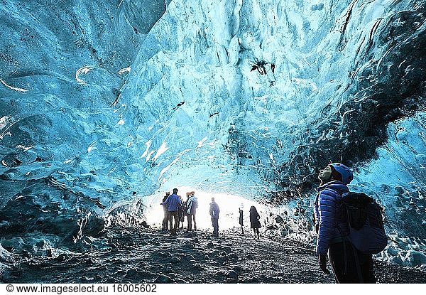 Tourists exploring a ice cave in Breidamerkurj?kull glacier  which is an outlet glacier of the larger glacier of Vatnaj?kull (region of Austurland  Iceland).