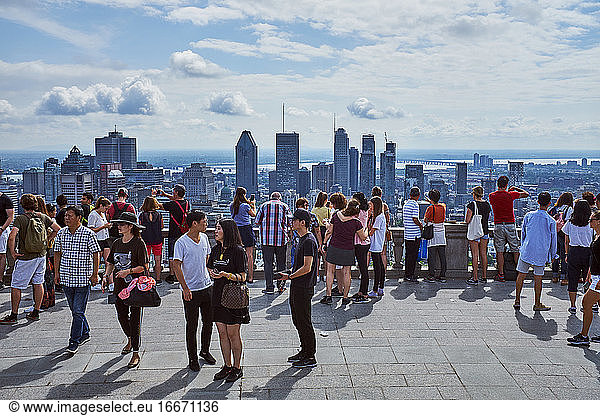 Tourists viewing city from hilltop on summer day