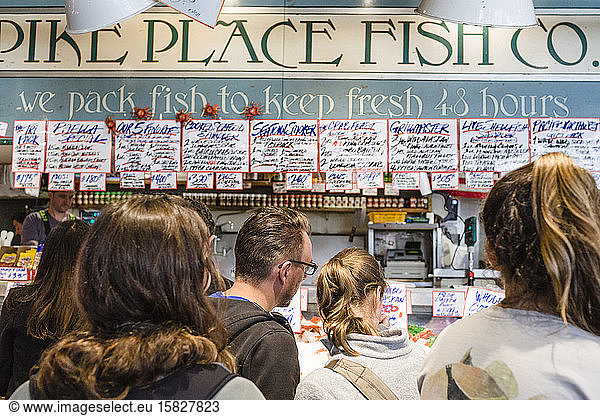 Tourists watch the fish throwers at the fish market  Pike Place Market