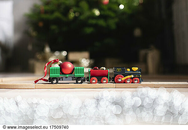 Toy train of wooden railway in front of Christmas tree